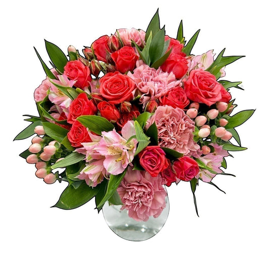 Flower Station bouquet with red roses, pink carnations, and blush alstroemeria in a glass vase.